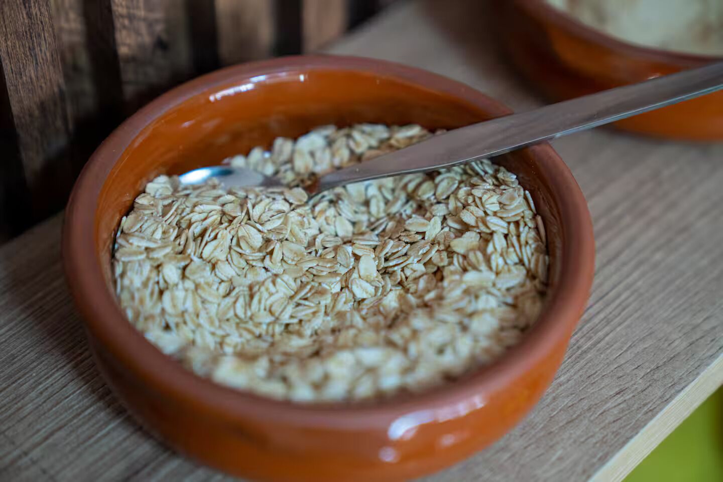 A bowl of oats with a spoon on a wooden surface.