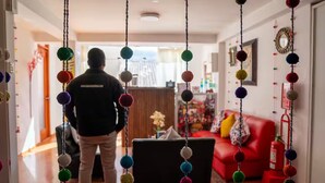 A person standing in a hallway with colorful hanging decorations, a red sofa, and a fire extinguisher in the background. - Family Apartment - - Bed and Breakfast in Cusco (Cusco)