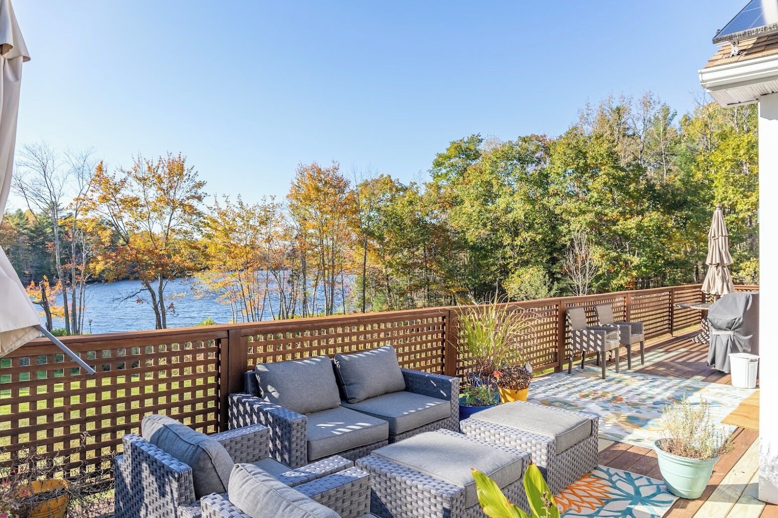 Une terrasse avec des meubles en osier, une vue sur un lac et une clôture en bois.