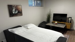 Une petite chambre comprenant un lit, une petite table, un téléviseur et une fenêtre.