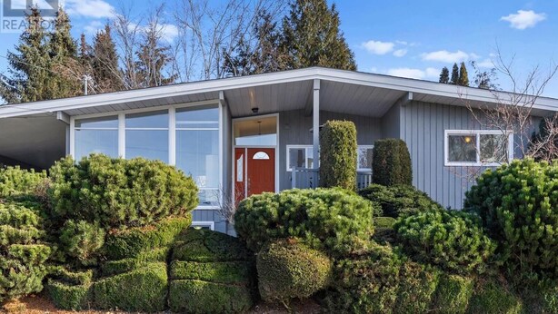 Une maison de plain-pied avec un porche couvert, une porte rouge et un garage.