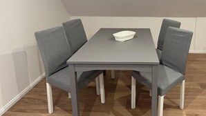 Une table à manger avec quatre chaises grises à revêtement rembourré et un panier tressé posé sur la table.