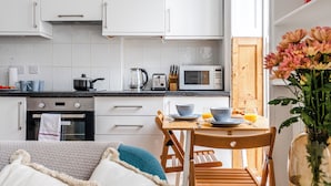 A modern kitchen with white cabinets, a microwave, a kettle, and a dining table with chairs. - The Russell Collection (London)