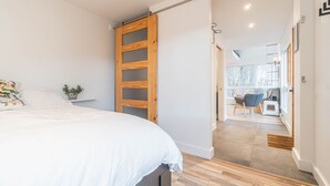 A bedroom with a bed, a wooden wardrobe, a small table with a plant, and a view of a dining area through an open door. - Superb views and literally 2 min walk to resort ! (Mont-Tremblant)