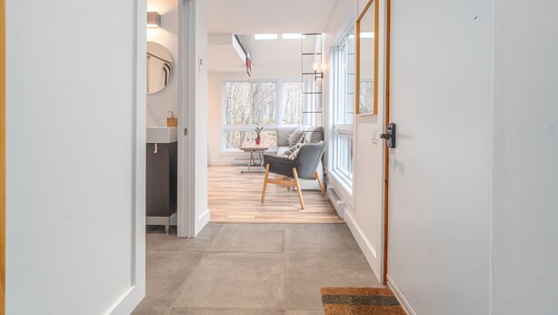 A hallway leading to a seating area with a view of trees through large windows. - Superb views and literally 2 min walk to resort ! (Mont-Tremblant)
