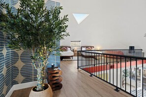 Un intérieur moderne avec un escalier en bois, un arbre en pot et une vue sur le paysage urbain.