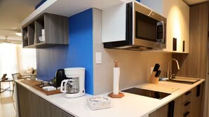 Una cucina moderna con un piano di lavoro bianco, una macchina per il caffè, un forno a microonde e un lavello.