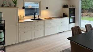 A modern kitchen with white cabinetry, a black countertop, and a built-in oven. - Beautiful home in Dronningmølle with WiFi (Dronningmølle)