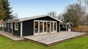 A single-story house with a deck, large sliding glass doors, and a small attached garage. - Beautiful home in Dronningmølle with WiFi (Dronningmølle)