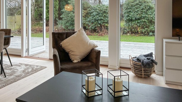 A modern living room with a leather armchair, a glass coffee table, and two candle holders. - Beautiful home in Dronningmølle with WiFi (Dronningmølle)
