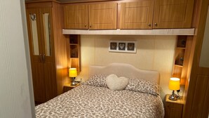 Une chambre à coucher comprenant un lit, deux lampes de chevet, une table de chevet, une armoire et une étagère avec des objets décoratifs.