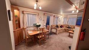Un espace de vie chaleureux comprenant un canapé, une table à manger avec des chaises et un petit coin cuisine.