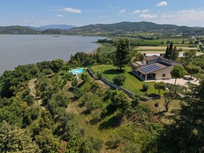 A house with a swimming pool, surrounded by lush greenery and a view of a lake and mountains. - Villa Melissa (Umbria)