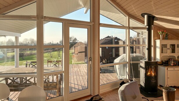 A spacious room with large windows, a fireplace, and a deck area. - Lovely home in Slagelse with WiFi (Slagelse)
