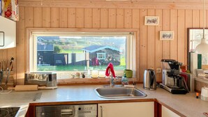 A kitchen with a large window, wooden walls, a Siemens dishwasher, a coffee maker, and a kettle. - Lovely home in Slagelse with WiFi (Slagelse)