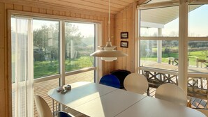 A wooden interior with a dining table and chairs, large windows, and a hanging light fixture. - Lovely home in Slagelse with WiFi (Slagelse)