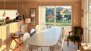 A wooden interior with a dining table, chairs, a kitchen area, and a large window offering a view of the outdoors. - Lovely home in Slagelse with WiFi (Slagelse)