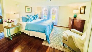 A bedroom with a bed, bedside tables, a chair, a dresser, and a window with curtains.