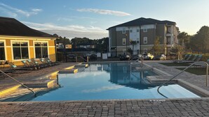 A swimming pool with lounge chairs, a brick pathway, and a building with multiple floors and balconies. - Coastal Comfort retreat offers 1 Bedroom, 1 Bathroom, and a Futon with Lakeview. (Jacksonville)