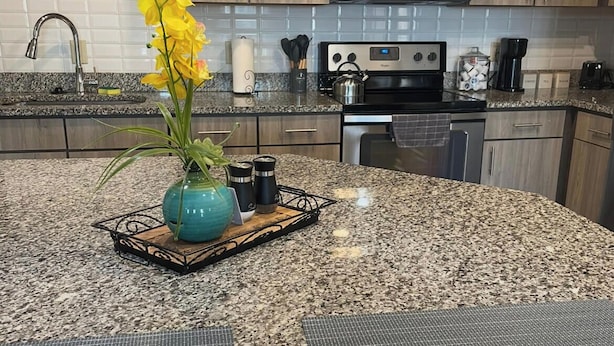 A kitchen with granite countertops, a microwave, a stove, and wooden cabinets. - Coastal Comfort retreat offers 1 Bedroom, 1 Bathroom, and a Futon with Lakeview. (Jacksonville)