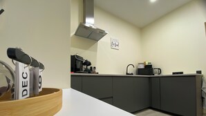 Una cocina moderna con encimera blanca, armarios oscuros y una cafetera.