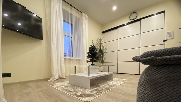 Una sala de estar moderna con un televisor de pantalla plana, un árbol de Navidad y un sofá grande de color gris.