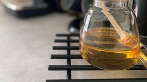 Un tarro de vidrio con una pajita de madera sobre una rejilla de metal negro.