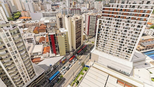 A high-rise building with multiple floors, a central courtyard, and a view of the surrounding cityscape. - Studio Pet Friendly c Garagem e Varanda no Centro (Juiz de Fora)