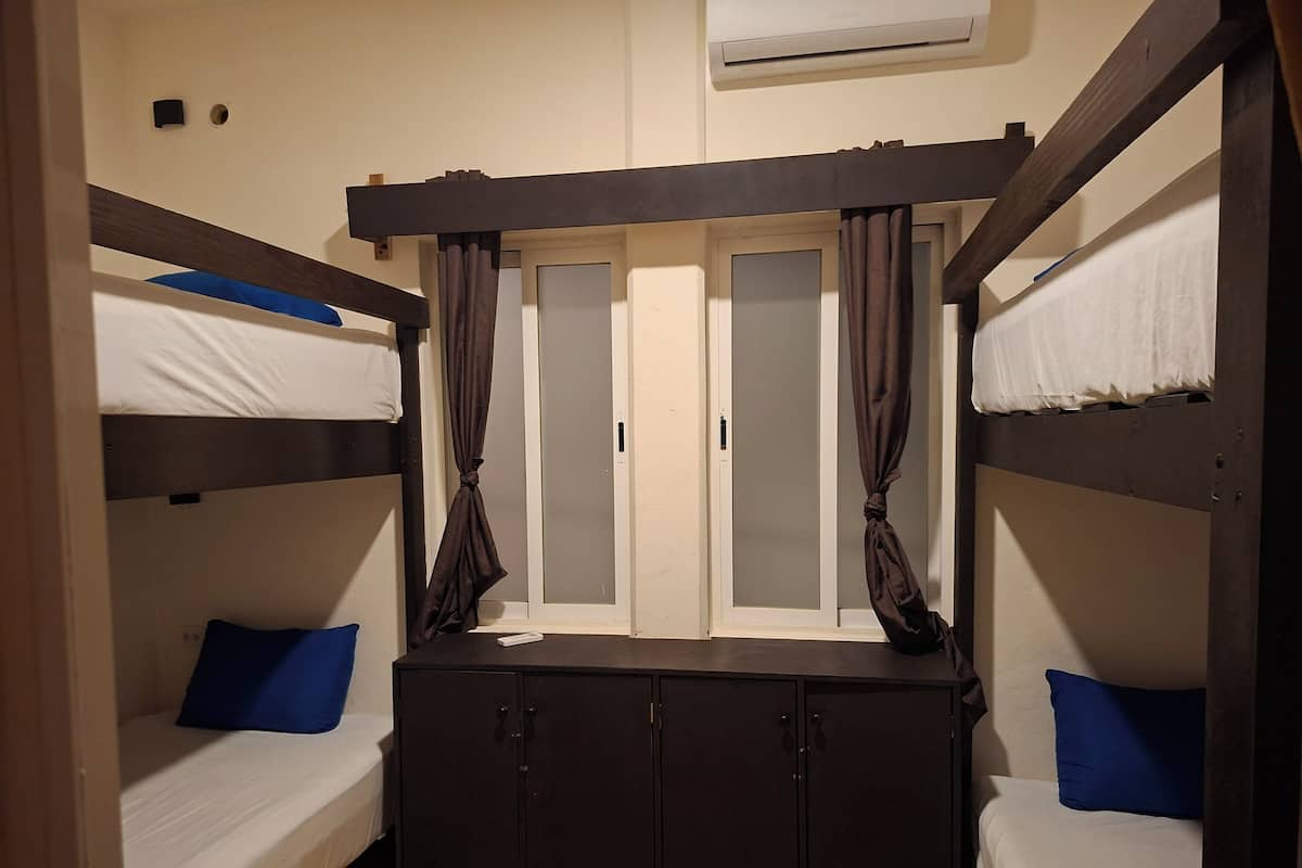 A room with bunk beds, a wardrobe, and a window with curtains.