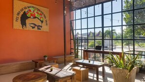 A cozy patio area with wooden furniture and a large window offering a view of the outside. - Casa Frida (Tulum)