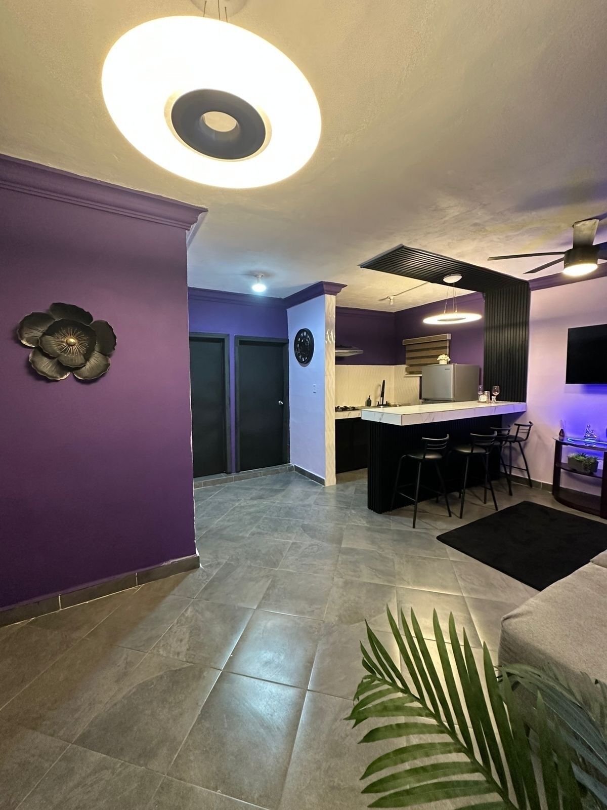 A modern kitchen with a central island, a dining area with chairs, and a ceiling fan.