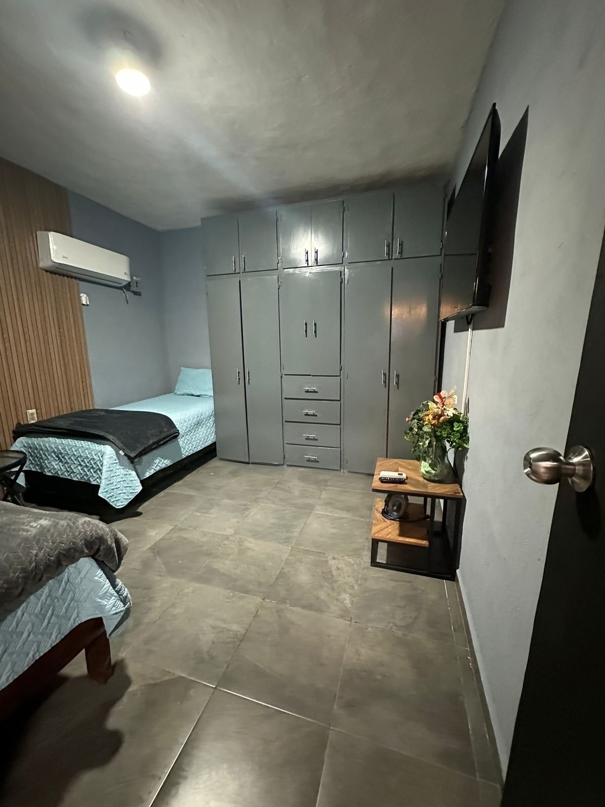 Una camera da letto con un letto, un armadio, un tavolino con un vaso e una TV a parete.