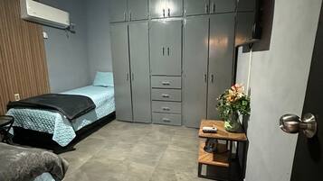 Una camera da letto con un letto, un armadio, un tavolino con un vaso e una TV a parete.