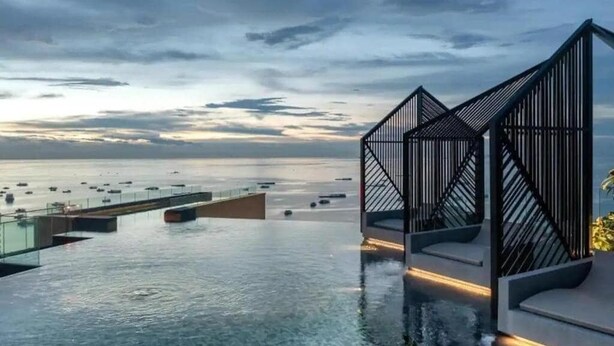 A modern infinity pool with a view of the sea and boats.
