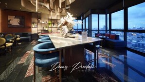 A modern hotel lobby with a high ceiling, a central bar area, and a seating arrangement.