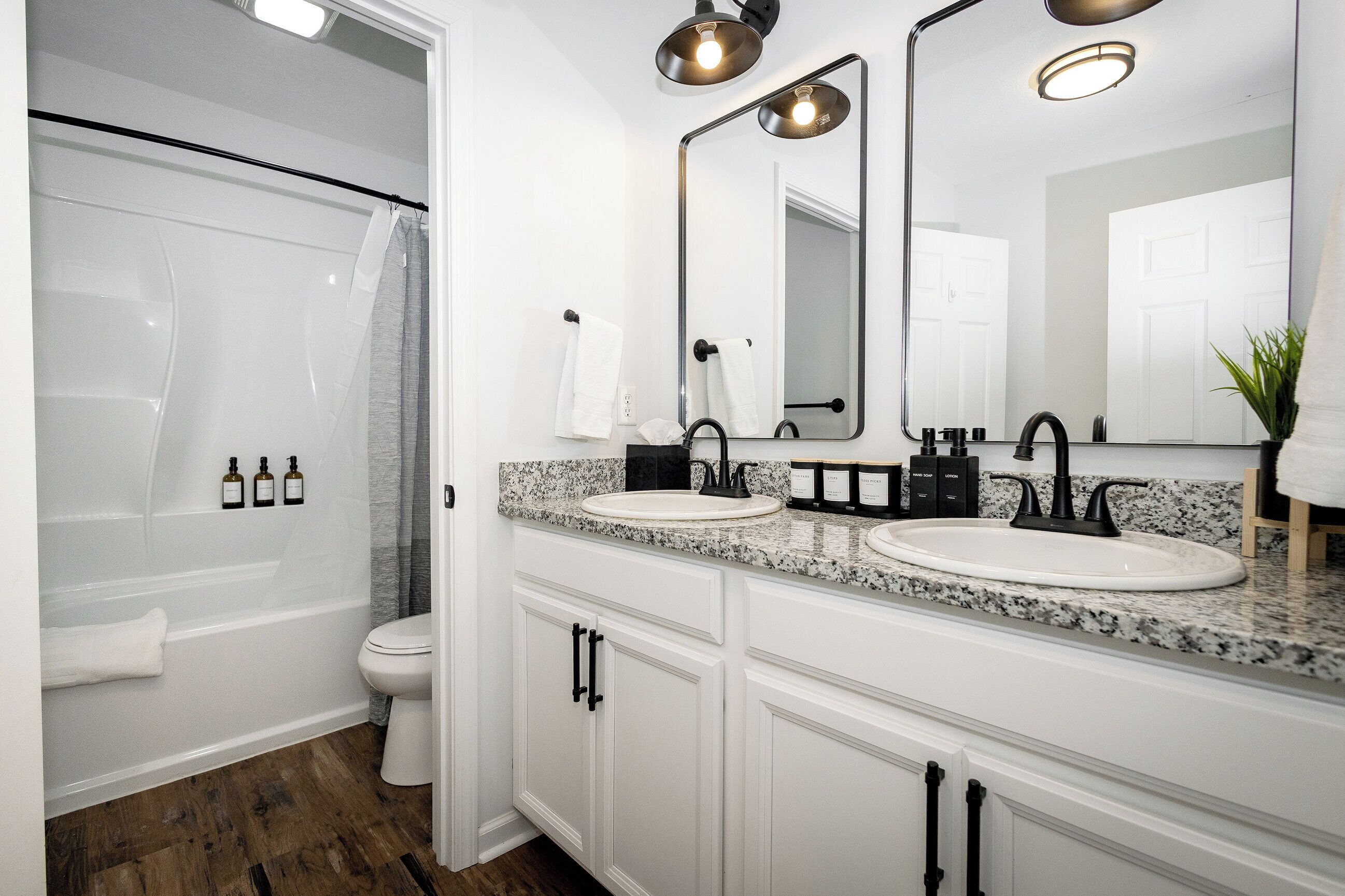 A modern bathroom with a walk-in shower, two sinks, and a large mirror.