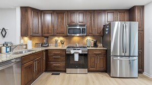 A modern kitchen with wooden cabinets, stainless steel appliances, and a granite countertop. - Amazing remodeled property in the Heart of Indy (Indianapolis)
