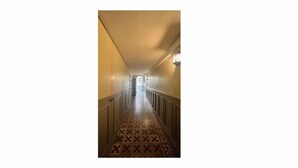 Un long couloir étroit, doté d’un revêtement de sol à motifs et d’un plafond de couleur claire.