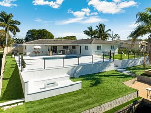A modern house with a swimming pool, patio, and a well-maintained lawn. - The Lux Escape Cape Coral Gulf Access and Boat lift (Cape Coral)