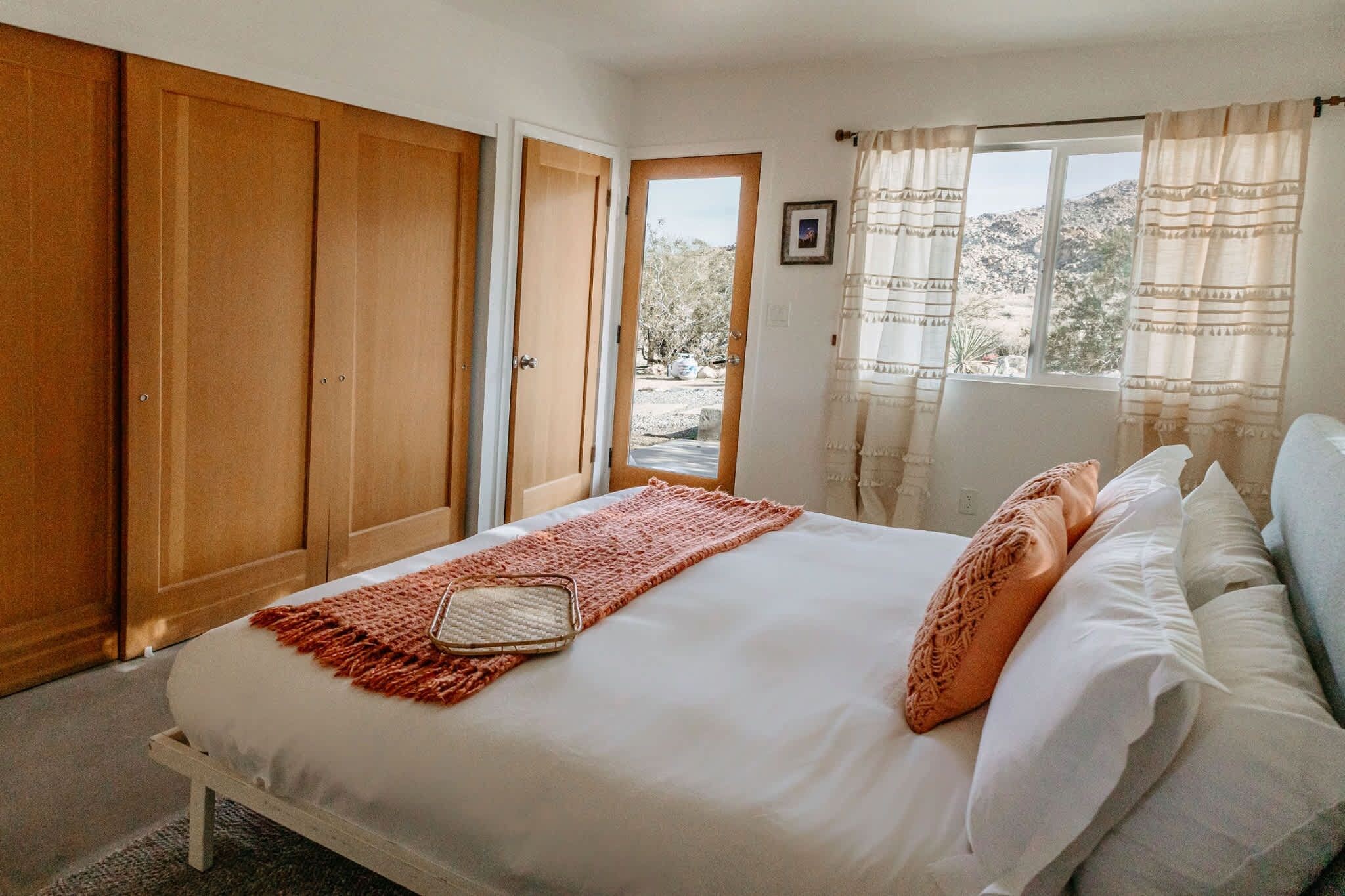 A bedroom with a bed, a window, and a door leading outside.