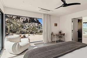 A modern bedroom with a large window, a bed, a desk, and a chair.