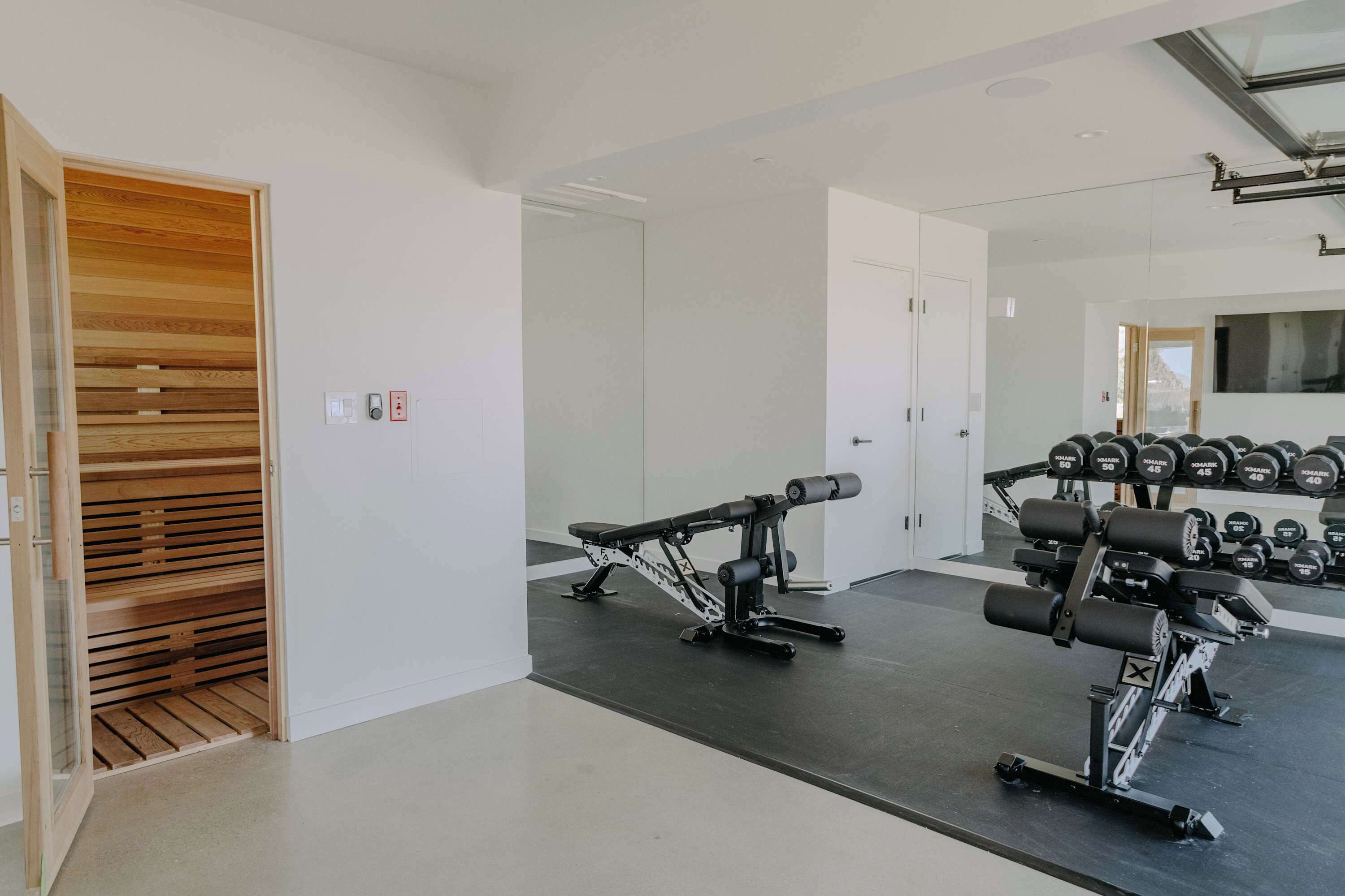 Un gimnasio con equipo de ejercicio, un armario de listones de madera y una pared espejada.