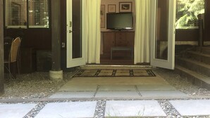 Un passage donnant sur une pièce où se trouvent un téléviseur, un banc et une petite table.