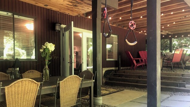 Un espace de restauration en plein air avec des chaises et une table en osier, un plafond en bois et une vue sur l’extérieur.