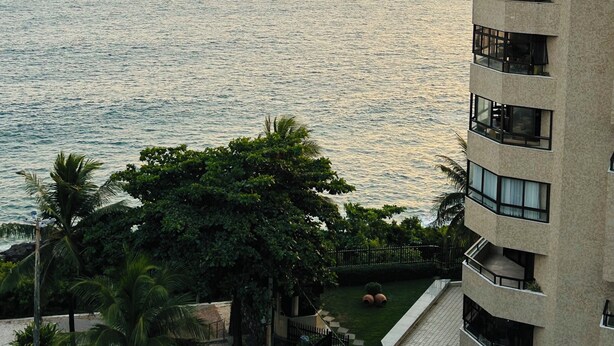 Un rascacielos con múltiples balcones que dan a una masa de agua al atardecer.