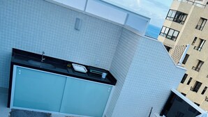 Terraza en la azotea con jacuzzi, zona de estar y cocina.