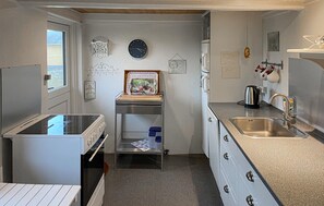 A compact kitchen with a sink, stove, and a small shelf. - Lovely home in Bagenkop with WiFi (Bagenkop)