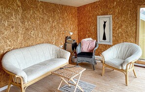 A cozy room with two white armchairs, a small wooden table, and a vintage radio. A framed picture of a black dress hangs on the wall. - Lovely home in Bagenkop with WiFi (Bagenkop)