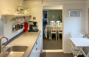A compact kitchen with a sink, coffee maker, and storage jars. A dining area with a table and chairs is visible in the background. - Lovely home in Bagenkop with WiFi (Bagenkop)