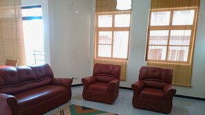 Un salon avec un canapé, deux fauteuils et un tapis à motifs.